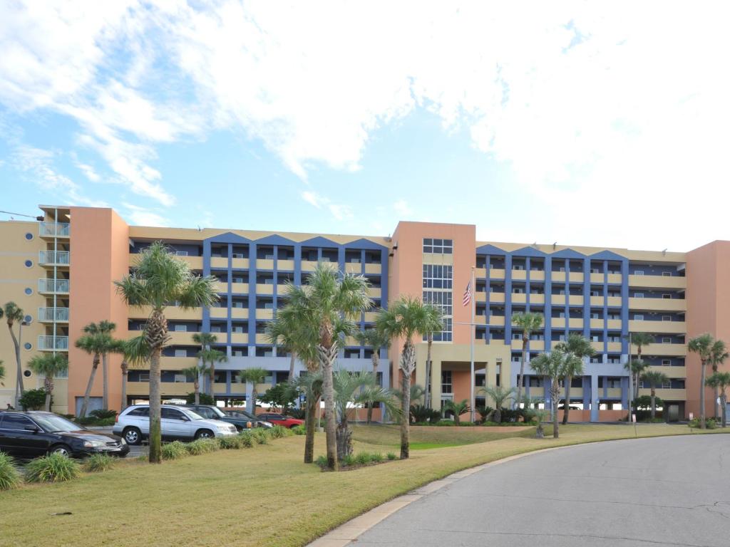 a large building with palm trees in a parking lot at Sea Oats II in Fort Walton Beach