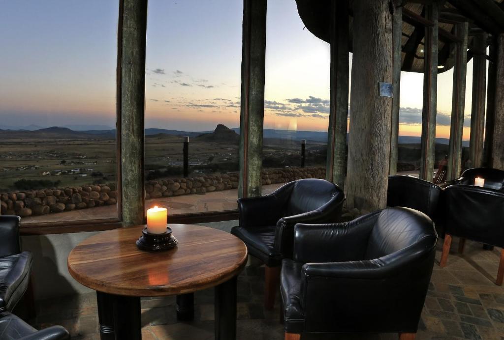 a room with chairs and a candle on a table at Isandlwana Lodge in Hlazakazi