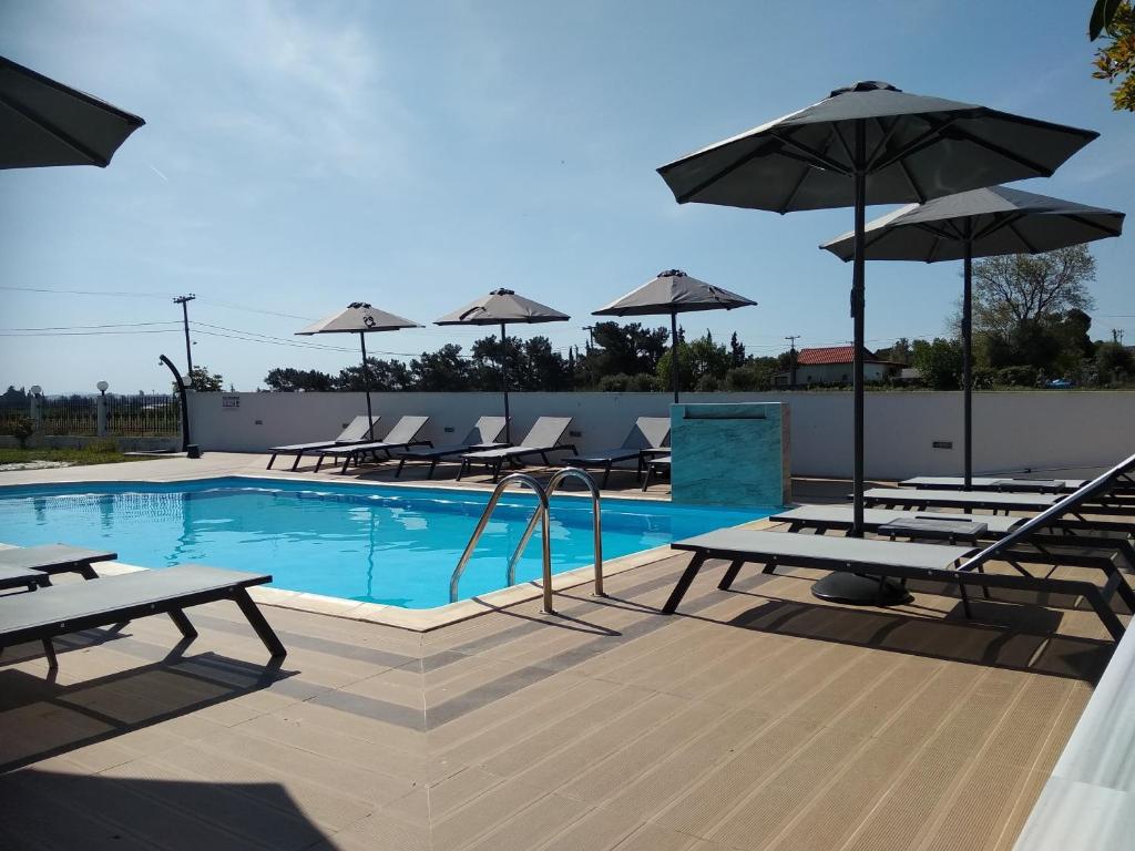 una piscina con sillas y sombrillas en una terraza en Villa Blue Apartments, en Agia Triada