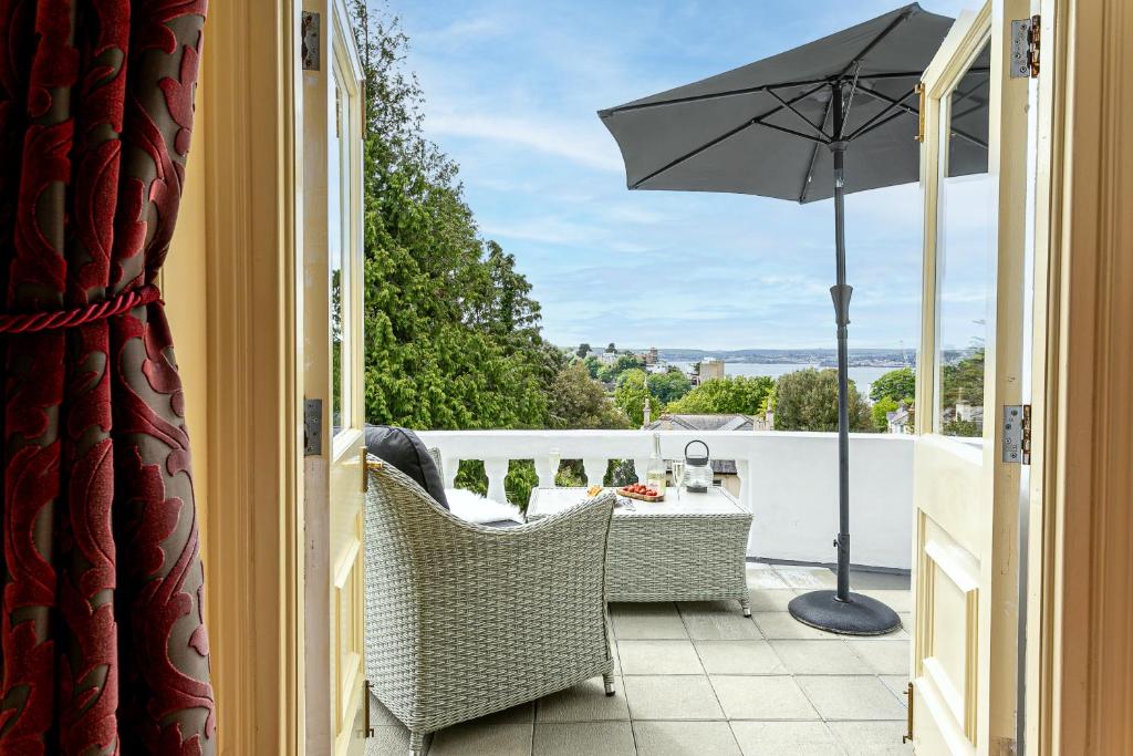 einen Balkon mit einem Tisch und einem Sonnenschirm in der Unterkunft Vomero Holiday Apartments in Torquay