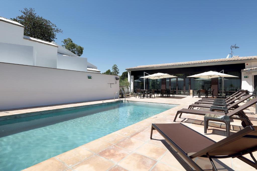 a swimming pool with chairs and umbrellas next to a building at Áurea Washington Irving by Eurostars Hotel Company in Granada