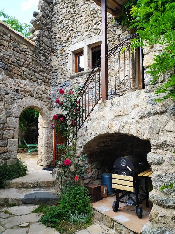 - un bâtiment en pierre avec un grill dans une cour dans l'établissement Les Châtaigniers Gîtes du Mas Haut, à Saint-Jean-du-Gard