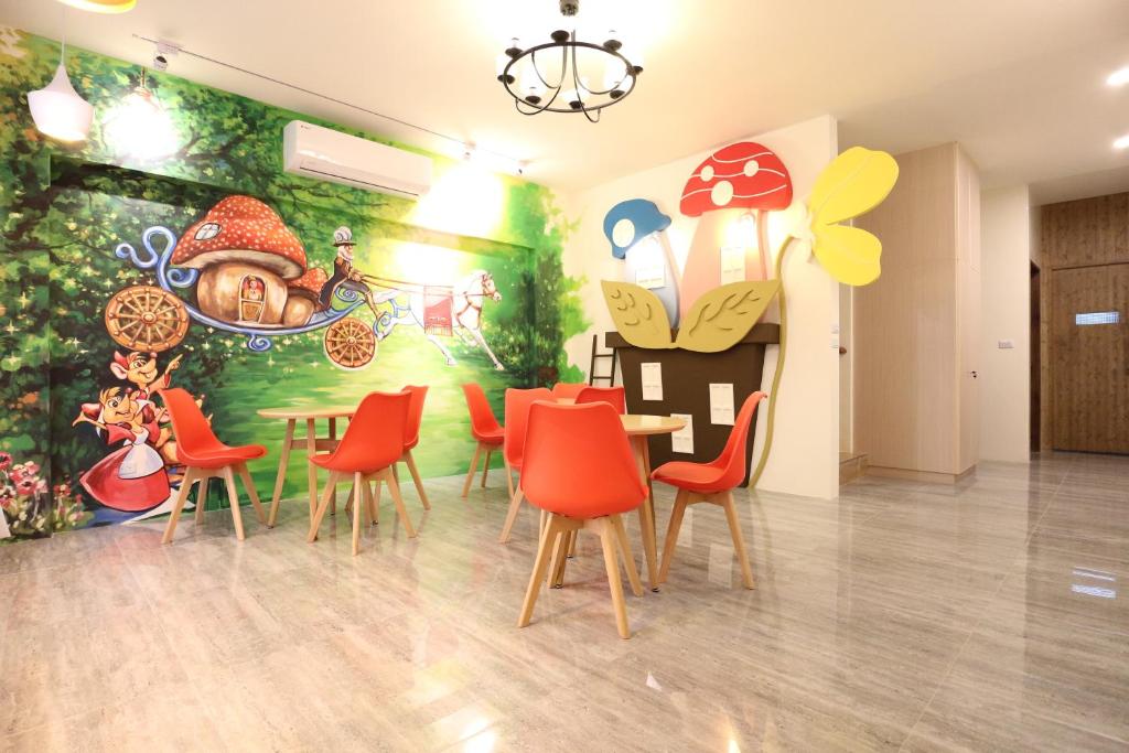 ein Esszimmer mit einem Tisch, Stühlen und einem Wandbild in der Unterkunft 蘑菇奇緣民宿 in Taitung