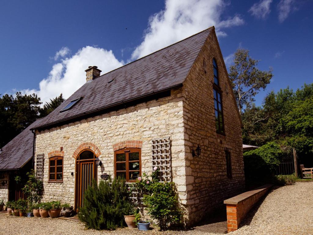 um pequeno edifício de tijolos com um telhado preto em Jasmine Cottage em Little Witcombe