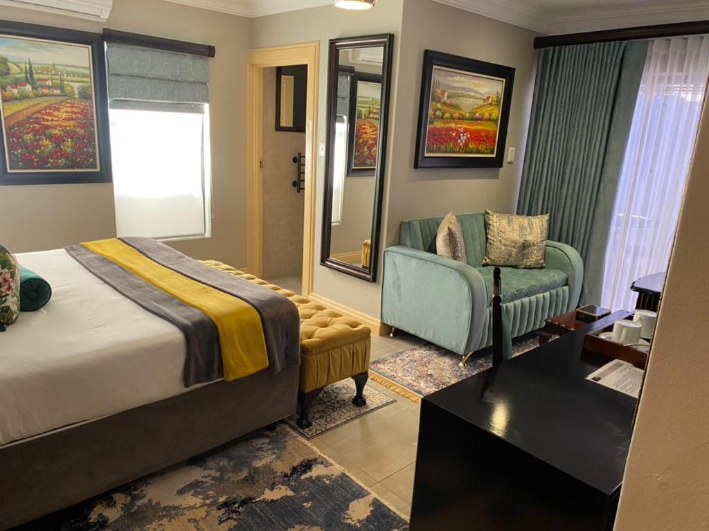 una camera da letto con un letto, un divano e una sedia di Sasavona Boutique Hotel a Polokwane