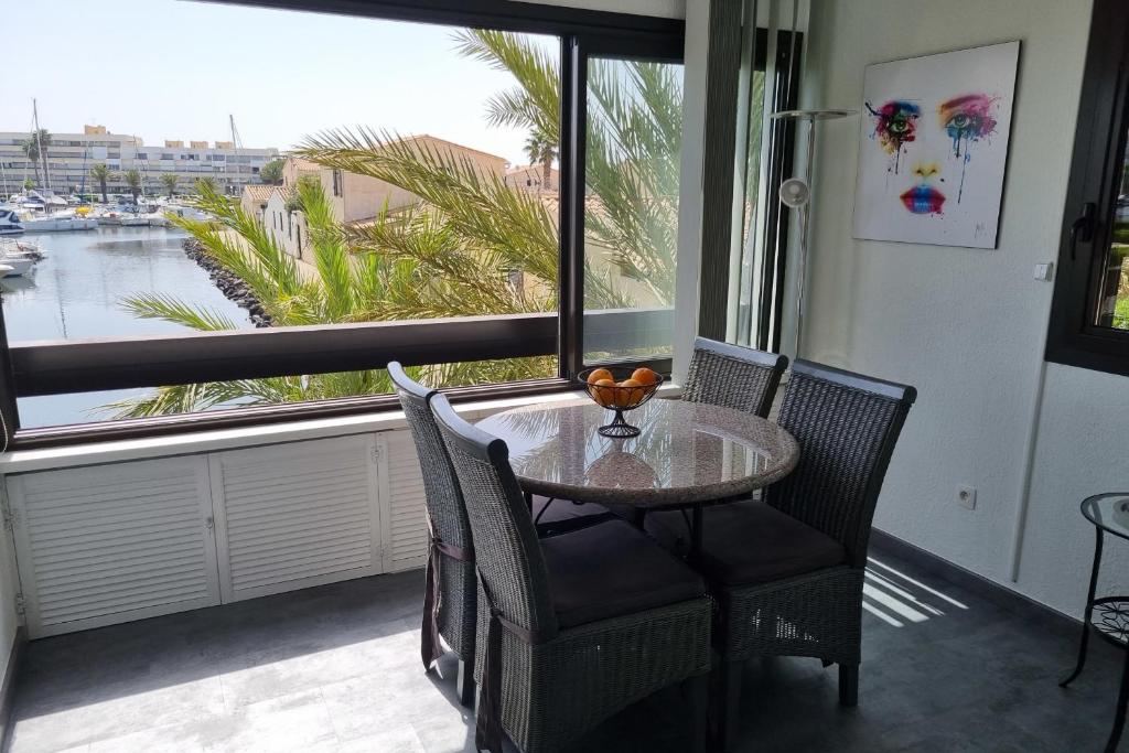une table et des chaises devant une grande fenêtre dans l'établissement Naturiste Cap d'Agde Port Vénus 110, au Cap d'Agde
