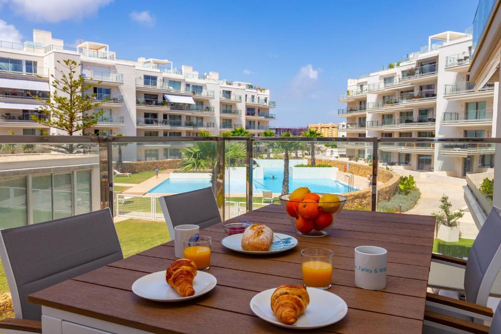 una mesa con platos de cruasanes y zumo de naranja en Denia Apartment Marina Real, en Denia
