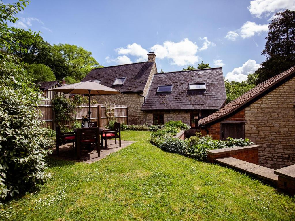 a garden with a table and an umbrella at Amber Cottage in Little Witcombe