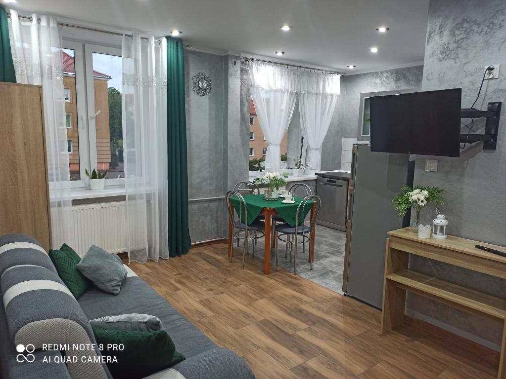 Silver Apartment Mazury Giżycko في غيجيتسكو: غرفة معيشة مع أريكة ومطبخ مع طاولة
