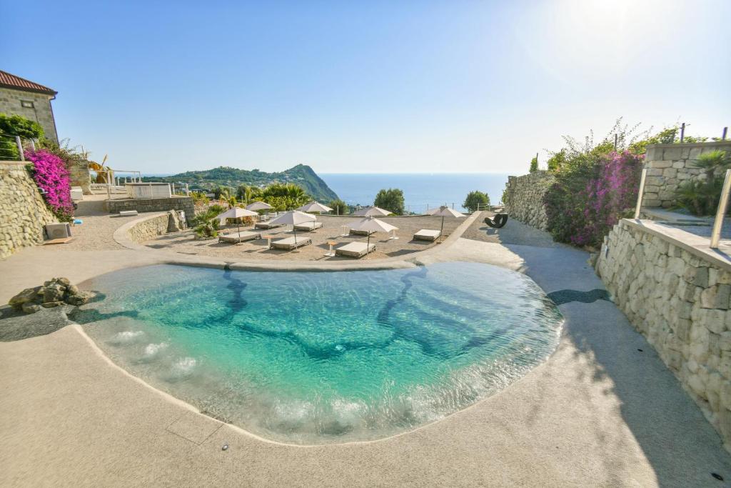 a swimming pool with chairs and the ocean in the background at Tenuta C'est la Vie in Ischia