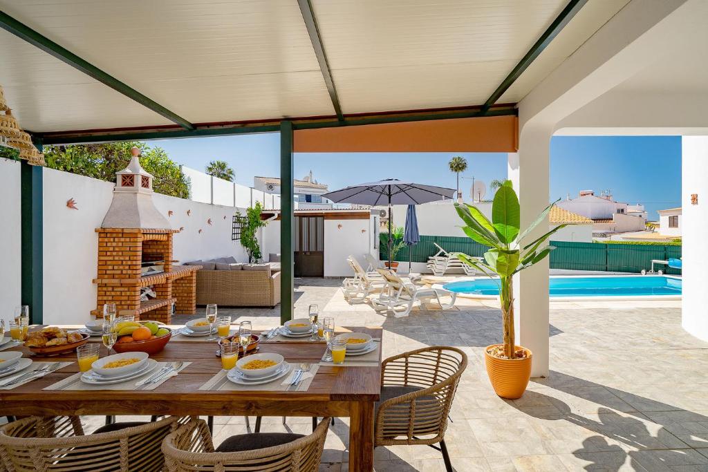 uma área de refeições exterior com uma mesa de madeira e cadeiras em Villa Harpista - Private pool and bbq em Albufeira
