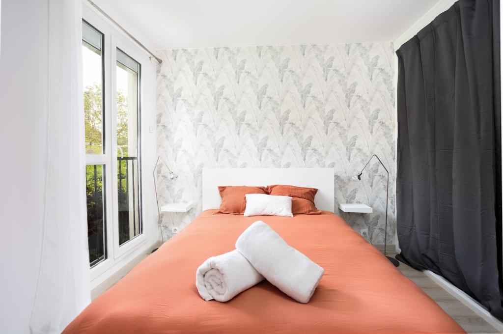 1 dormitorio con 1 cama grande de color naranja y 2 almohadas en LeCosyMelunais : Parking gratuit + Balcon aménagé, en Melun