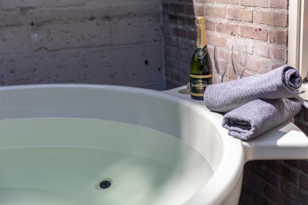 a bath tub with a towel and a bottle of champagne at Museumhuisje 013 in Tilburg