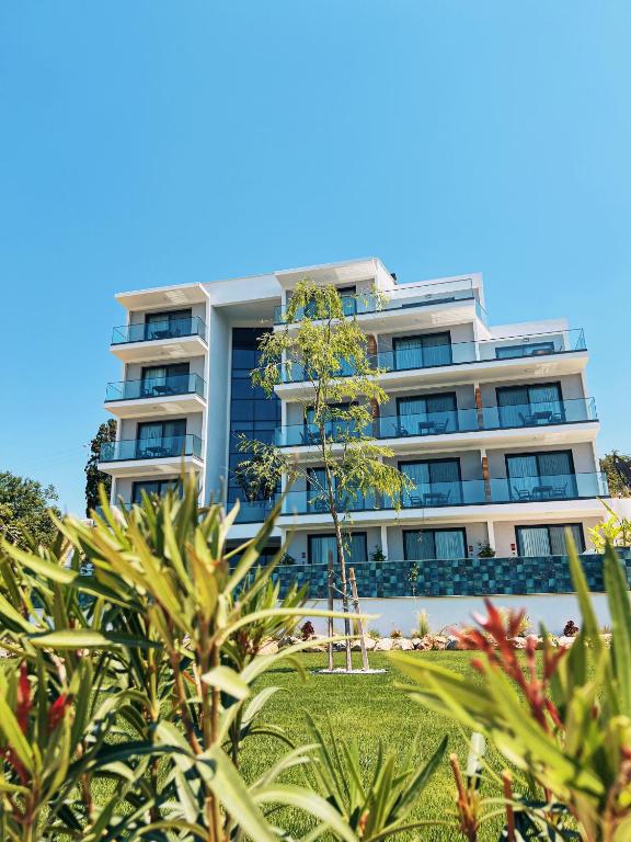 a tall building with a palm tree in front of it at KADAGAN SUİTES AYASARANDA in Çeşme