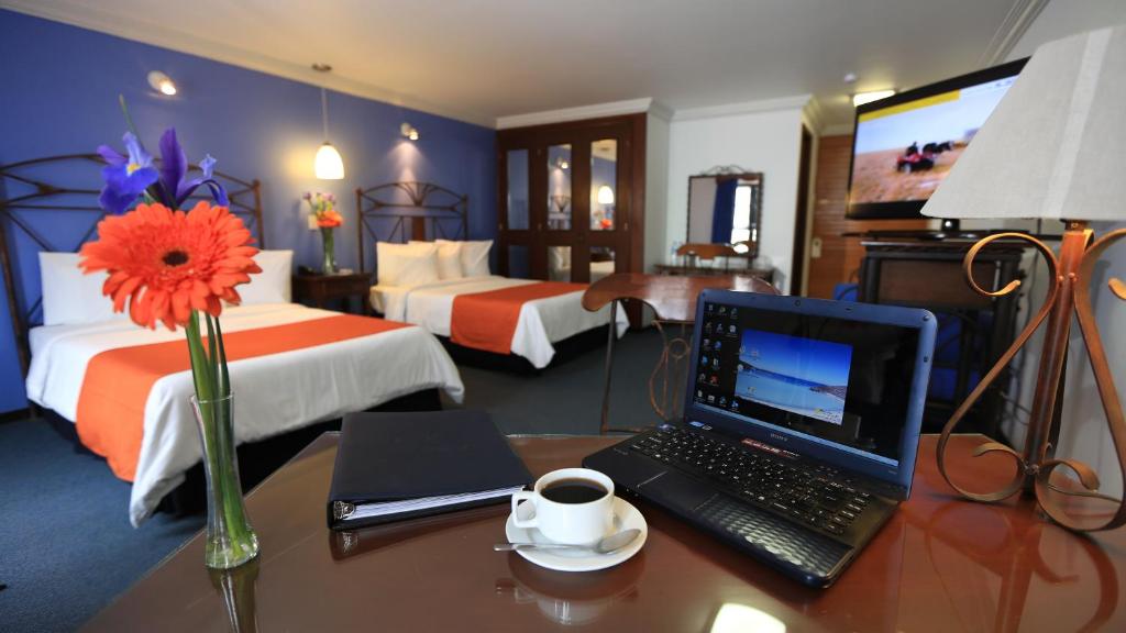 a hotel room with a desk with a laptop and a cup of coffee at Hotel Ciros in Pachuca de Soto