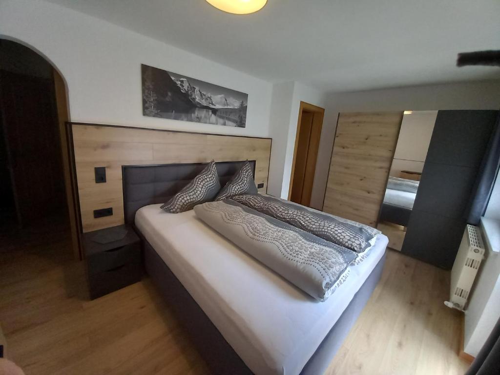 a bedroom with a large bed with a wooden headboard at Haus Waldfriede in Sankt Leonhard im Pitztal