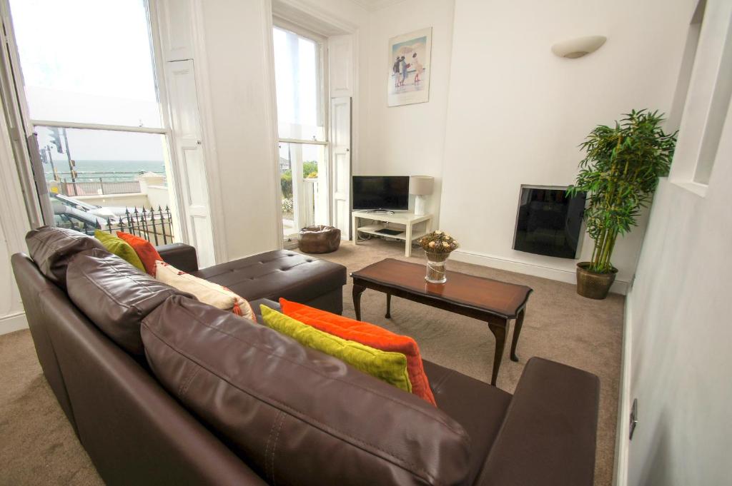 ein Wohnzimmer mit einem braunen Ledersofa und einem Tisch in der Unterkunft Marine Parade Sea View - by Brighton Holiday Lets in Brighton & Hove