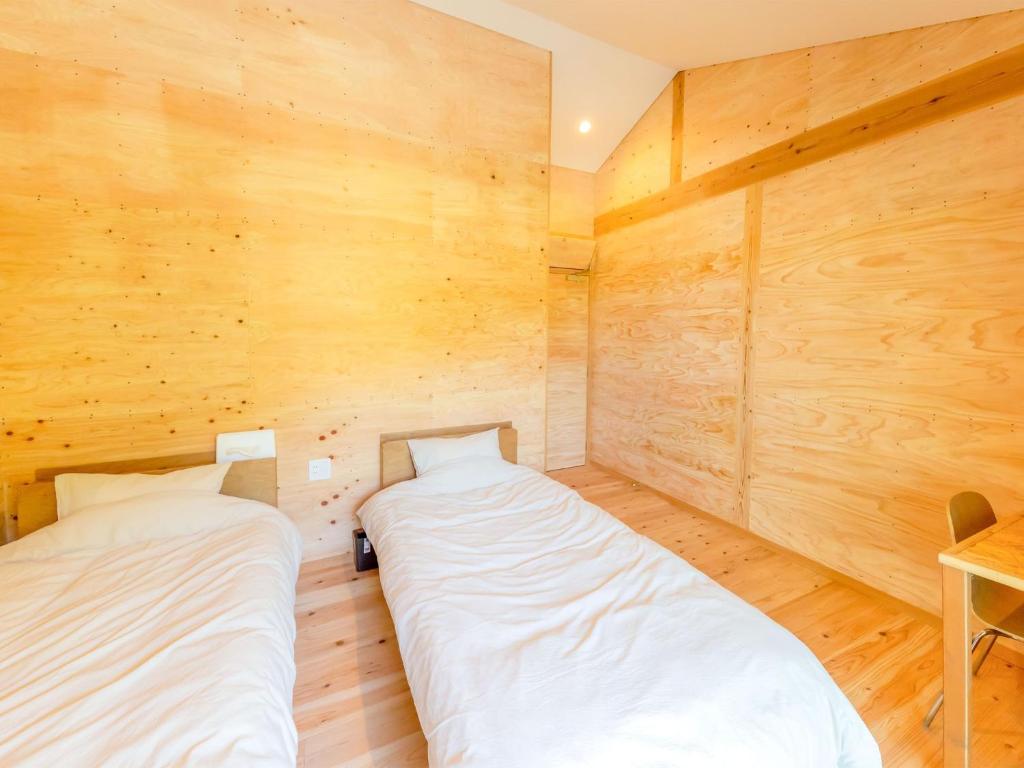 two beds in a room with wooden walls at Guest House Amami Long Beach 2 - Vacation STAY 37966v in Amami