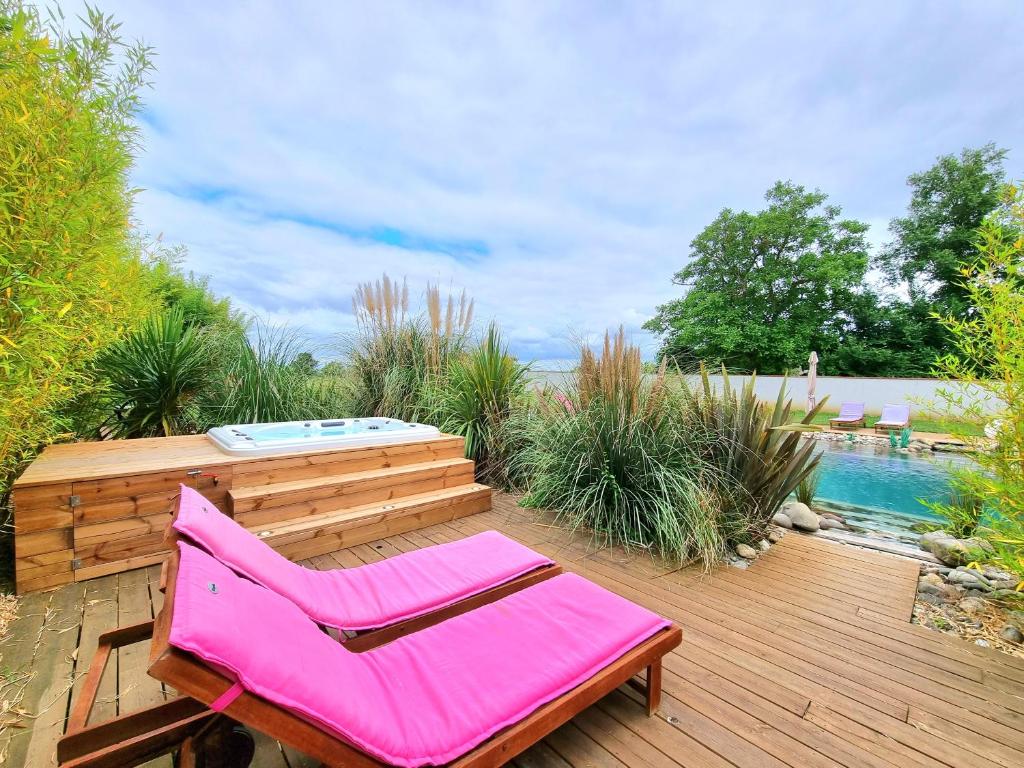 a pink chair sitting on a wooden deck next to a pool at Les Granges de Jules in Lafitte-Vigordanne