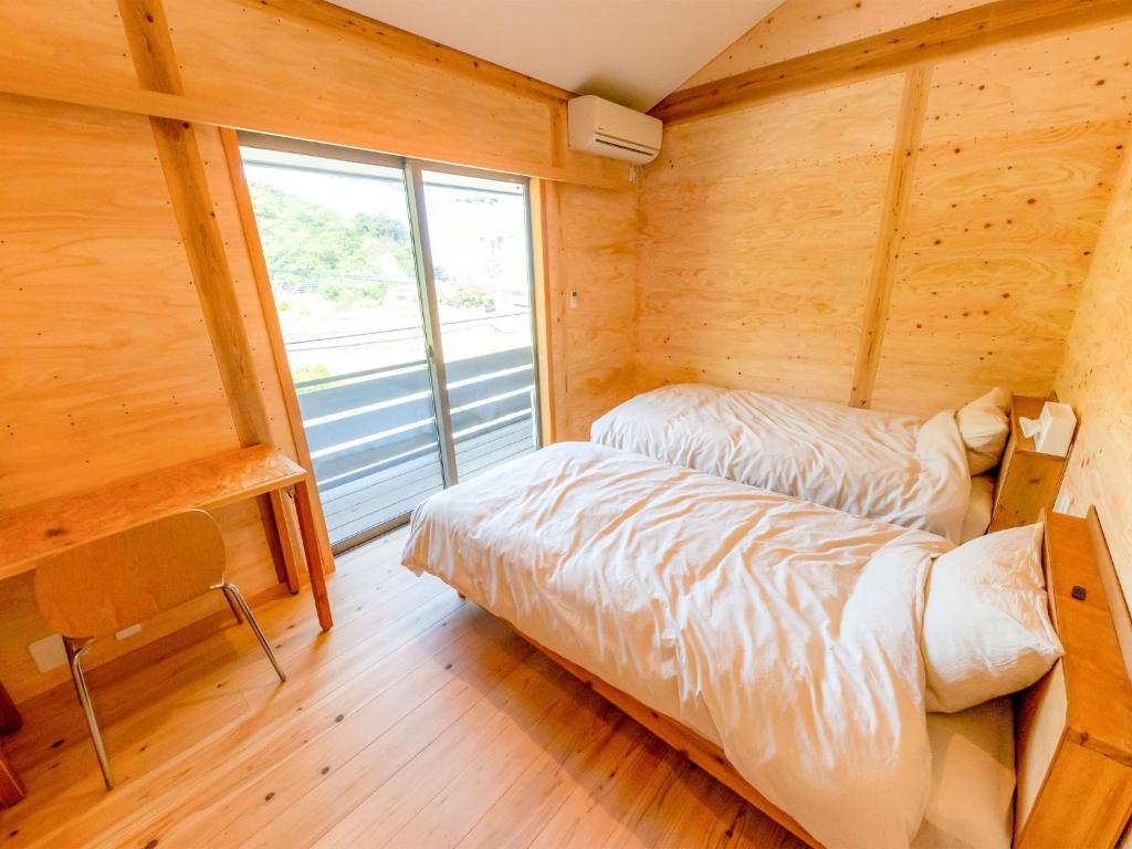 Habitación con 2 camas en una habitación de madera con ventana en Guest House Amami Long Beach 2 - Vacation STAY 37974v, en Amami
