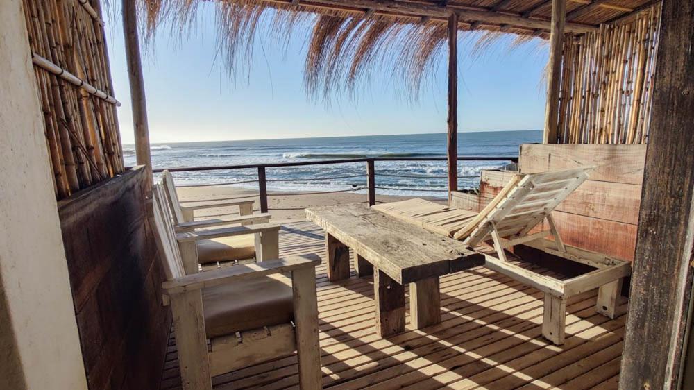 una veranda in legno con tavolo e sedie sulla spiaggia di Playa Luna Roja a Chapadmalal