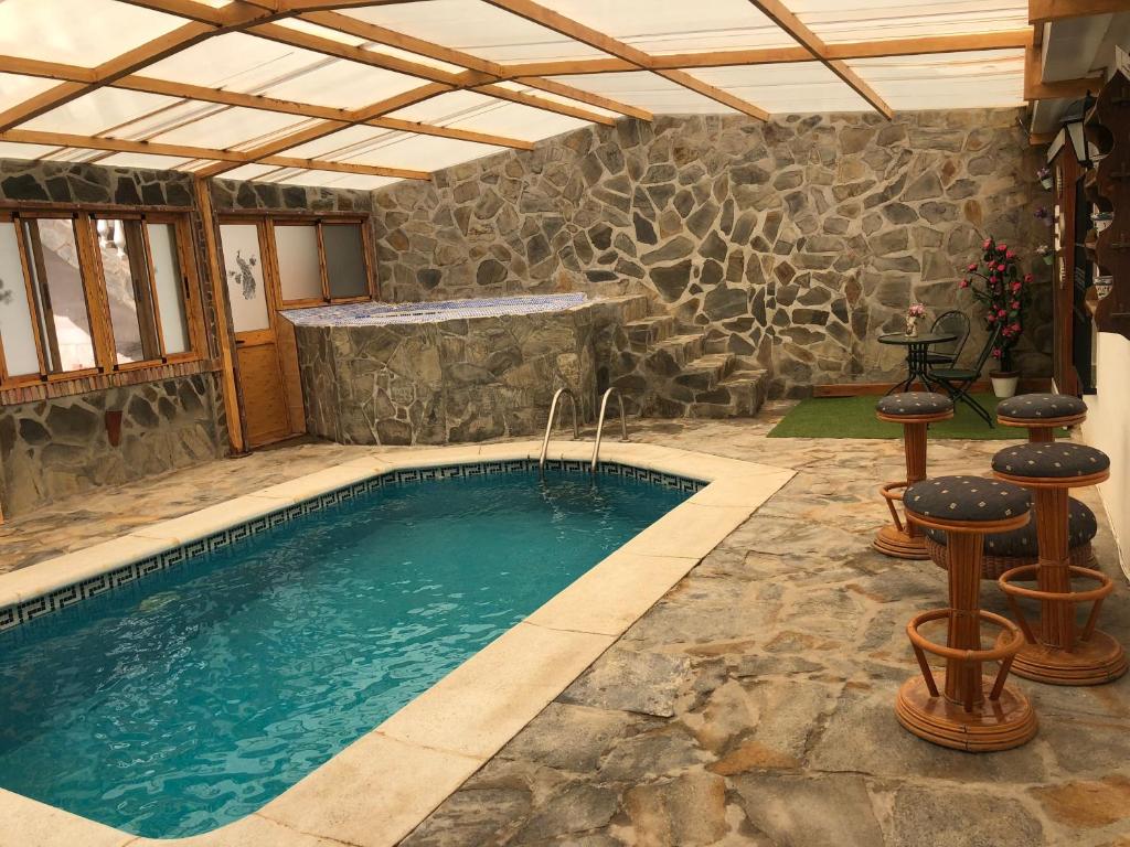 a swimming pool with a stone wall at Casa rural Cristina- Piscina climatizada in Málaga