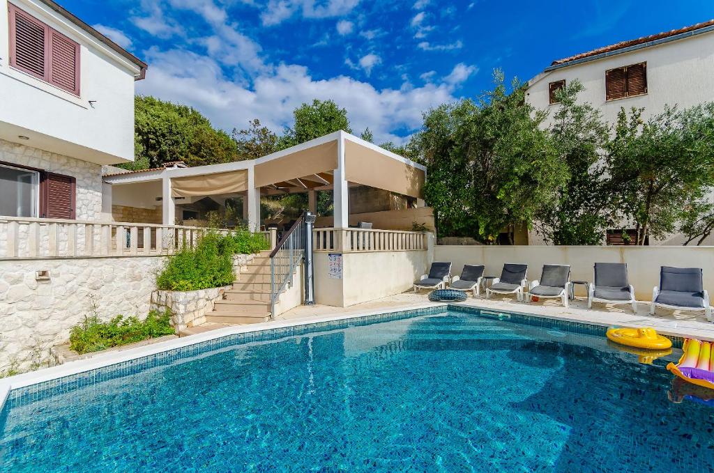 uma piscina com cadeiras e uma casa em Villa Damjan em Trogir