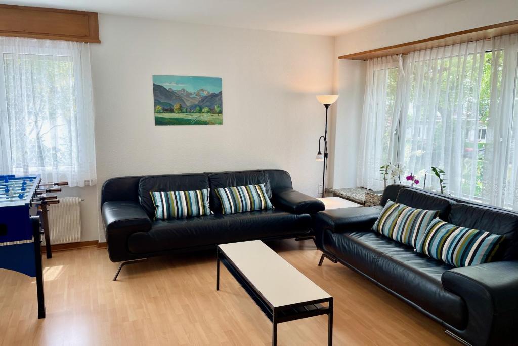 a living room with black leather couches and a table at alscher's holiday home in Interlaken