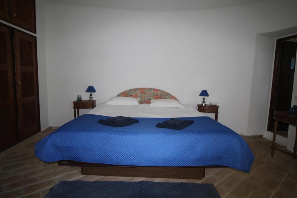 a bedroom with a large bed with blue sheets at Casa do Milho in Carvoeiro