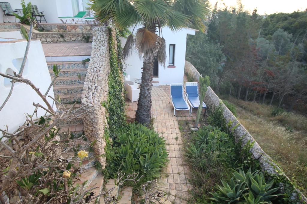 a house with two chairs and a palm tree at Casa do Milho in Carvoeiro