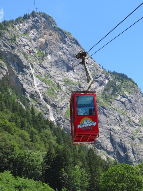 a red cable car in front of a mountain at Hotel Sonnwendhof Engelberg in Engelberg