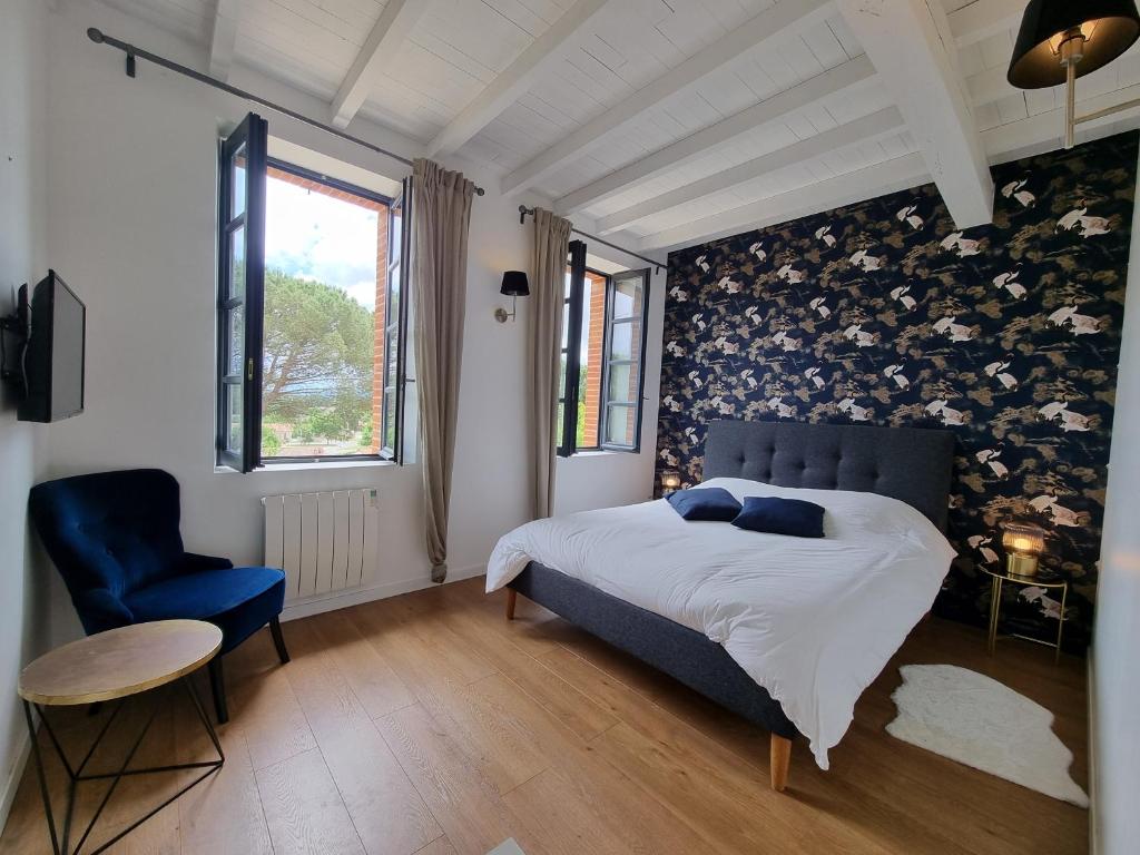 a bedroom with a bed and a blue chair at Les Granges de Jules in Lafitte-Vigordanne