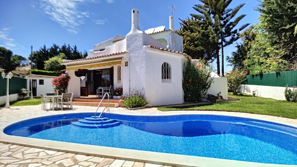 a villa with a swimming pool in front of a house at Villa Palmeira Galé Beach in Albufeira