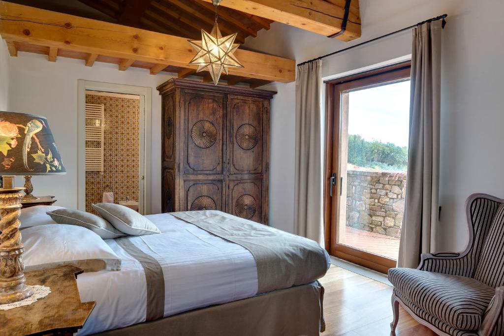 a bedroom with a bed and a chair and a window at Terre di Baccio in Greve in Chianti