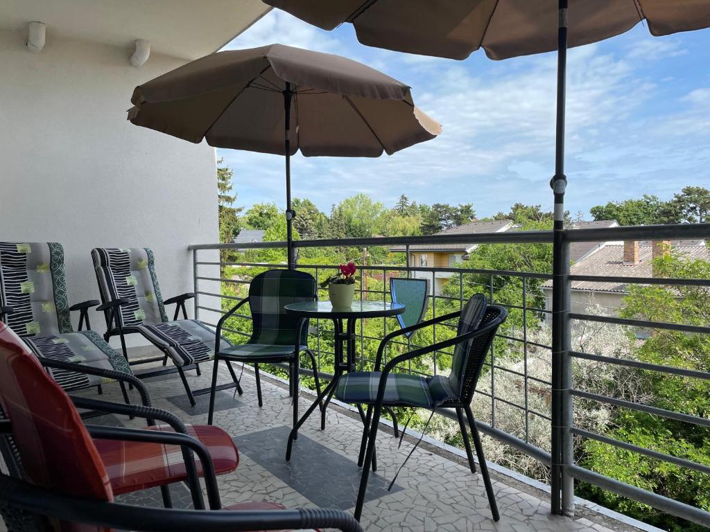 einen Balkon mit Stühlen, einem Tisch und einem Sonnenschirm in der Unterkunft Studió Apartmanok in Balatonfüred