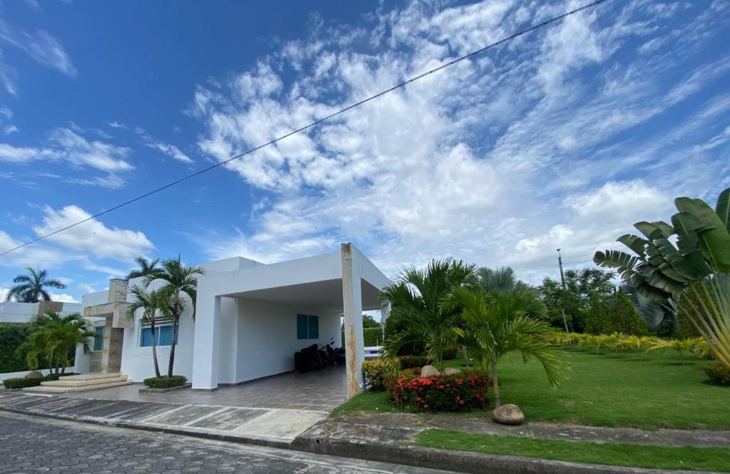 a white house with a yard with palm trees at Casa Piscina Girardot Condominio Campestre in Flandes