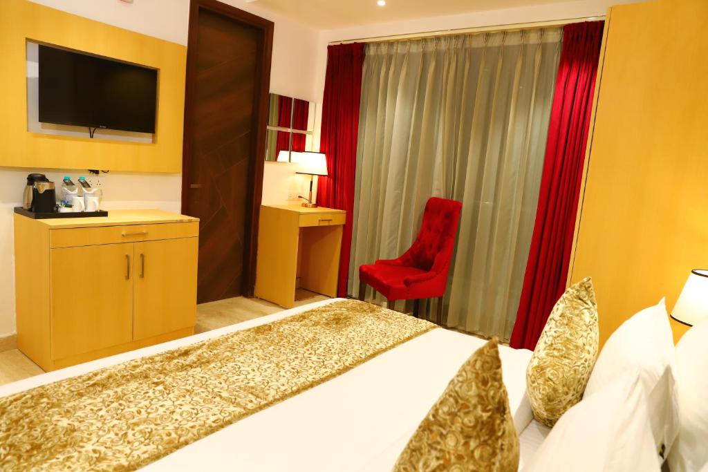 Habitación de hotel con cama y silla roja en Hotel Malbork Inn Rajouri Garden Delhi - Couple Friendly Local IDs Accepted en Nueva Delhi