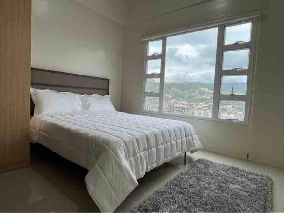 a bedroom with a bed and a large window at 1BR Unit - MIGAs Haven @ One Pavilion Place in Cebu City