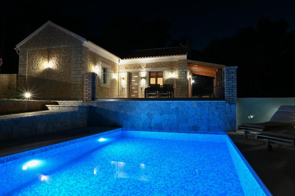 una piscina frente a una casa por la noche en Villa Ioanna, en Liapades