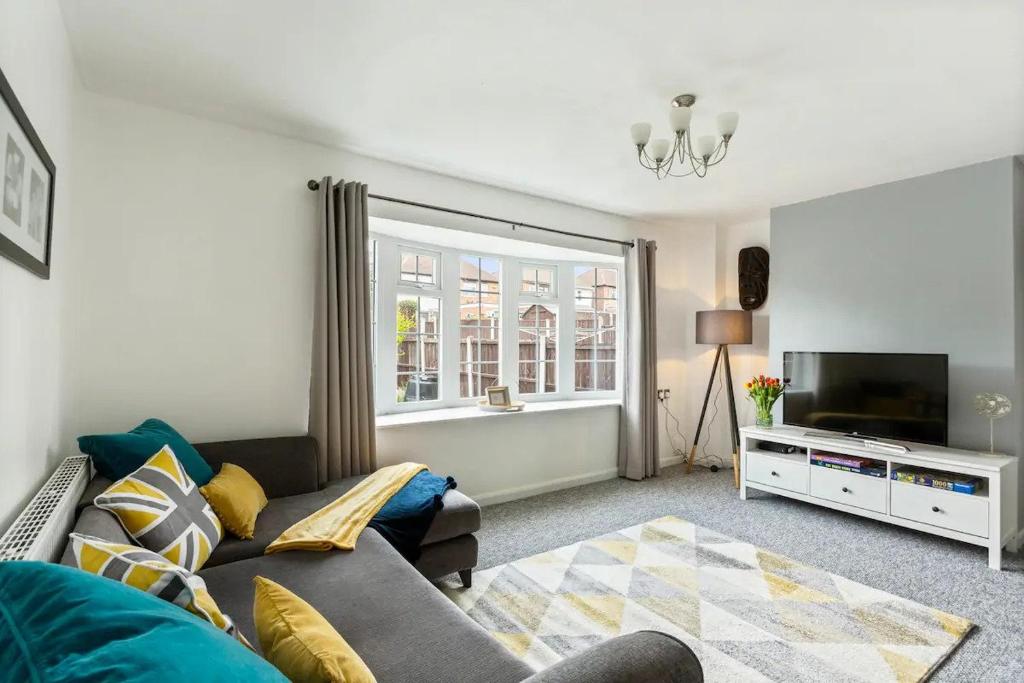 a living room with a couch and a tv at Bright & Spacious with Garden & Parking in Nottingham