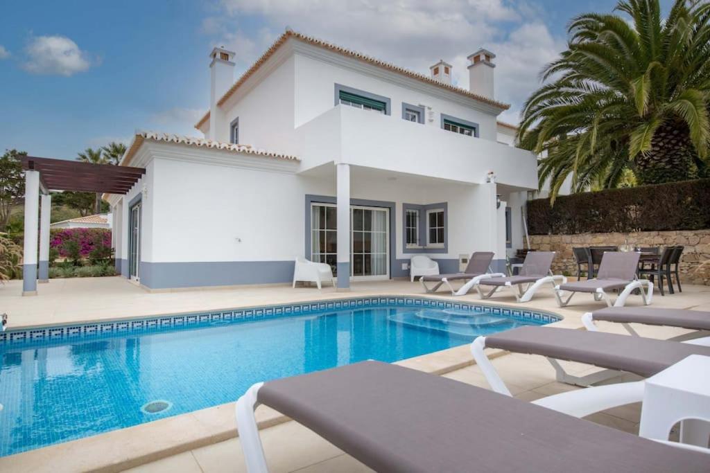 une villa avec une piscine en face d'une maison dans l'établissement Villa Estrella - Praia da Luz, à Luz