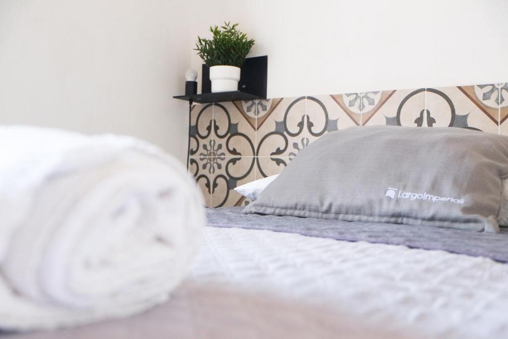 アヴェトラーナにあるLargo Imperiali B&Bの白いベッド1台、壁に植物が備わるベッドルーム1室が備わります。