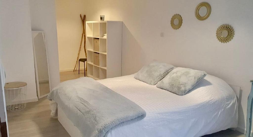 uma cama branca com 2 almofadas num quarto em Chez Marie et Seb em Pomérols