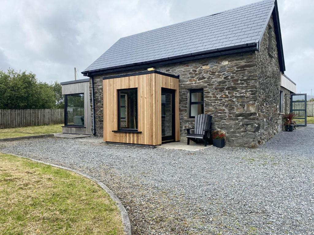 a small stone cottage with a bench in front of it at Cottage 426 - Moyard in Moyard