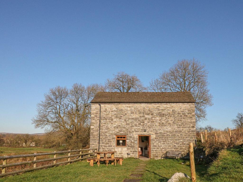 a stone building with a picnic table in a field at Columbine Barn in Bradwell