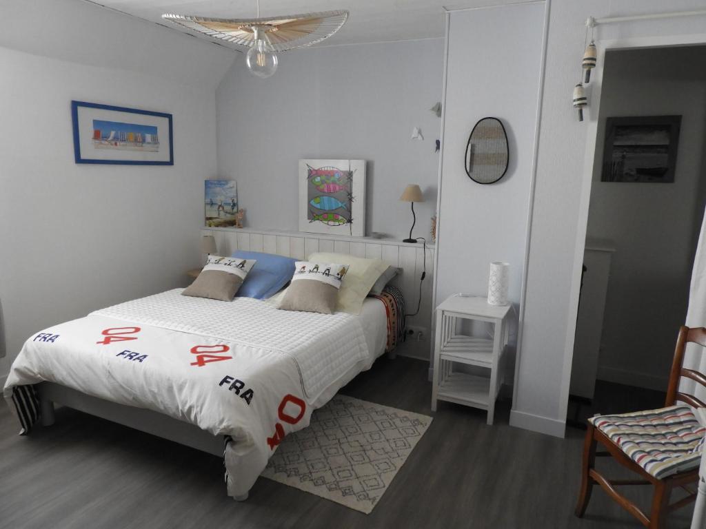 a bedroom with a bed and a chair at les volets bleus in Saint-Guénolé