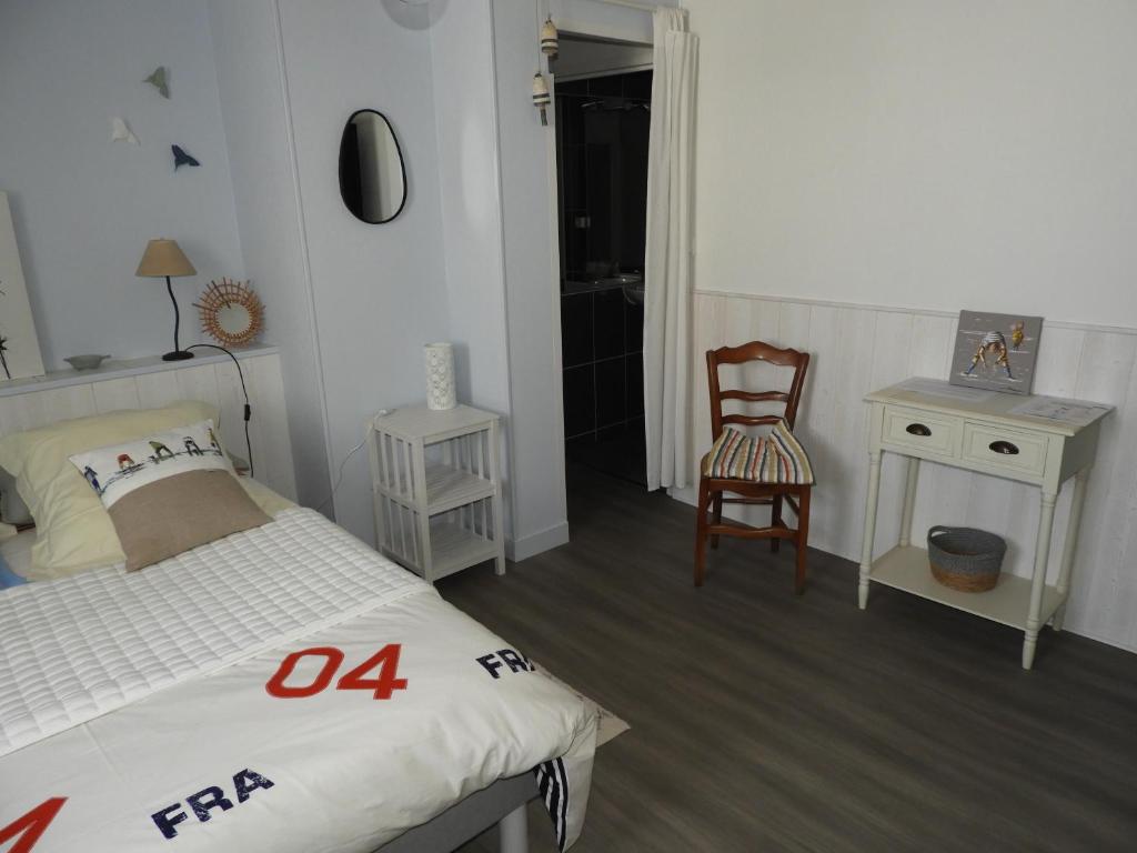 a bedroom with a bed and a chair and a table at les volets bleus in Saint-Guénolé