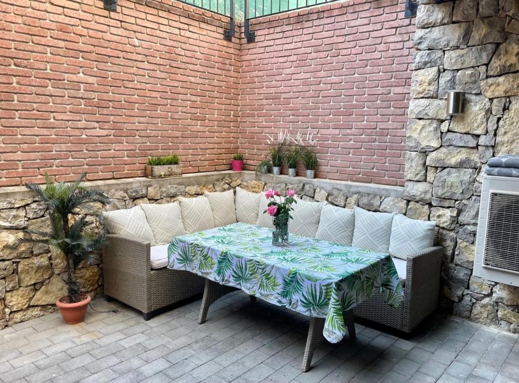 a patio with a table and a couch and a brick wall at Emifüred in Balatonfüred