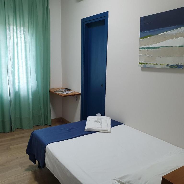 ein Schlafzimmer mit einem weißen Bett und einem blau-grünen Vorhang in der Unterkunft Hotel Pixunte in Policastro Bussentino