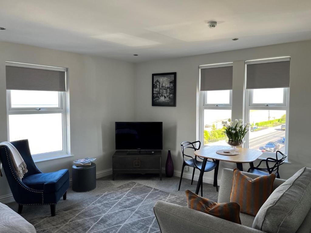 a living room with a couch and a table and windows at Seafront Luxury Apartment in Cleethorpes